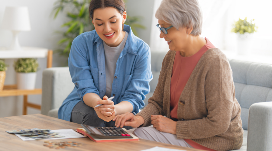 two women on a living room table looking at a calculator, budgetting